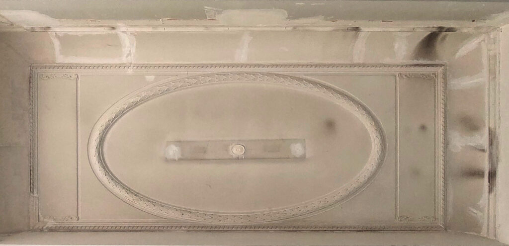 Gerestaureerd plafond met mouluren en ornamenten.